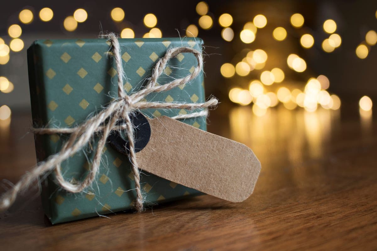 Wrapped gift beside outdoor gear on a wooden table